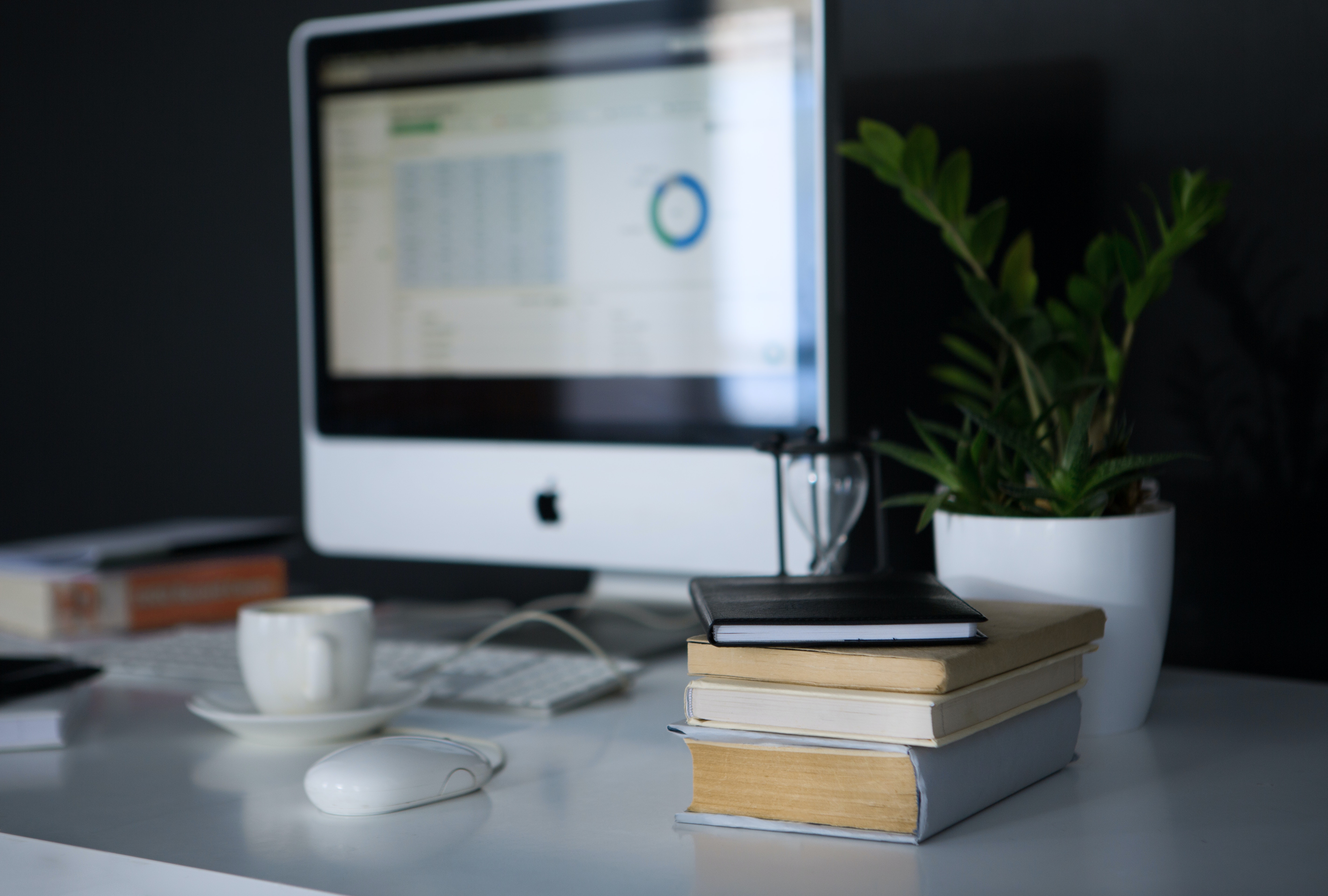 iMac sur un bureau à côté d'une pile de livres